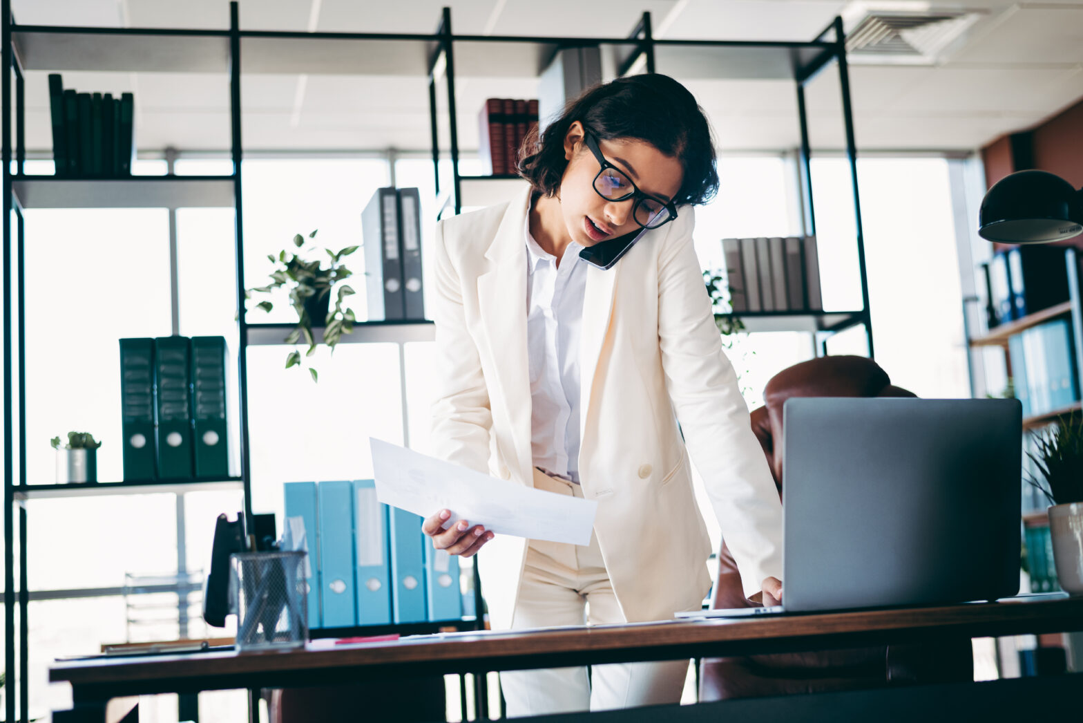 obieta w biurze prowadzi rozmowę telefoniczną i pracuje przy laptopie – symbol integracji firmowej telefonii z Microsoft Teams Phone.